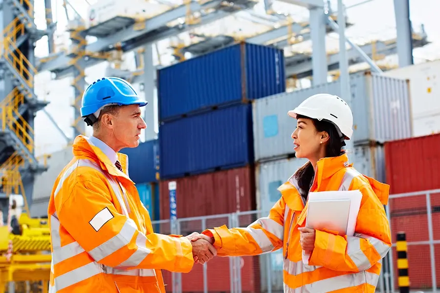 Two engineers shaking hands at a container terminal