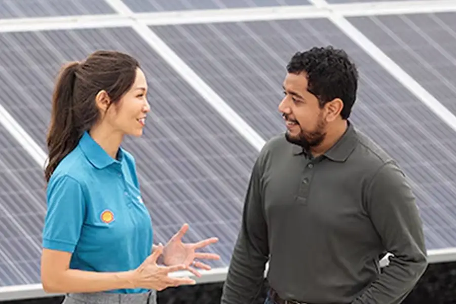 Shell-Mitarbeiter und Kunde im Gespräch vor einer Solar­anlagen-Installation.