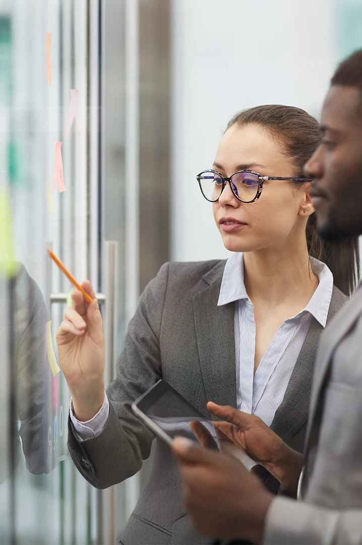 Business team planning operational costs on a glass board