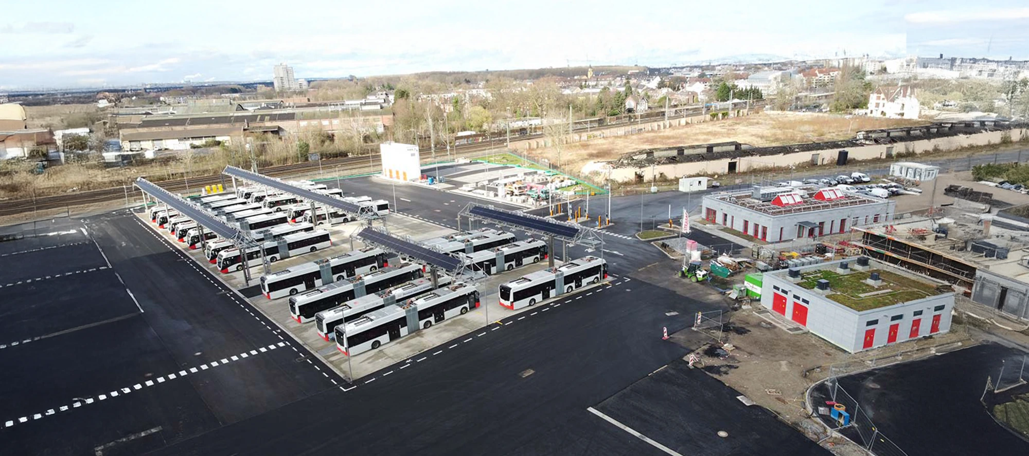 Luftaufnahme des neuen E-Bus-Depots der KVB in Köln-Porz mit Ladeinfrastruktur und begrünten Gebäudedächern.