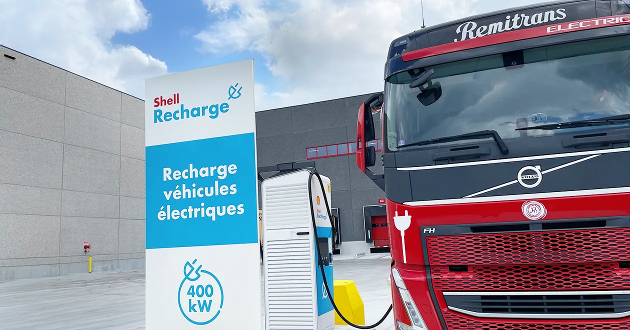 Nahaufnahme einer Shell Recharge 400-kW-Ladestation vor einem roten Elektro-Remitrans-Lkw im neu eröffneten halböffentlichen Depot.