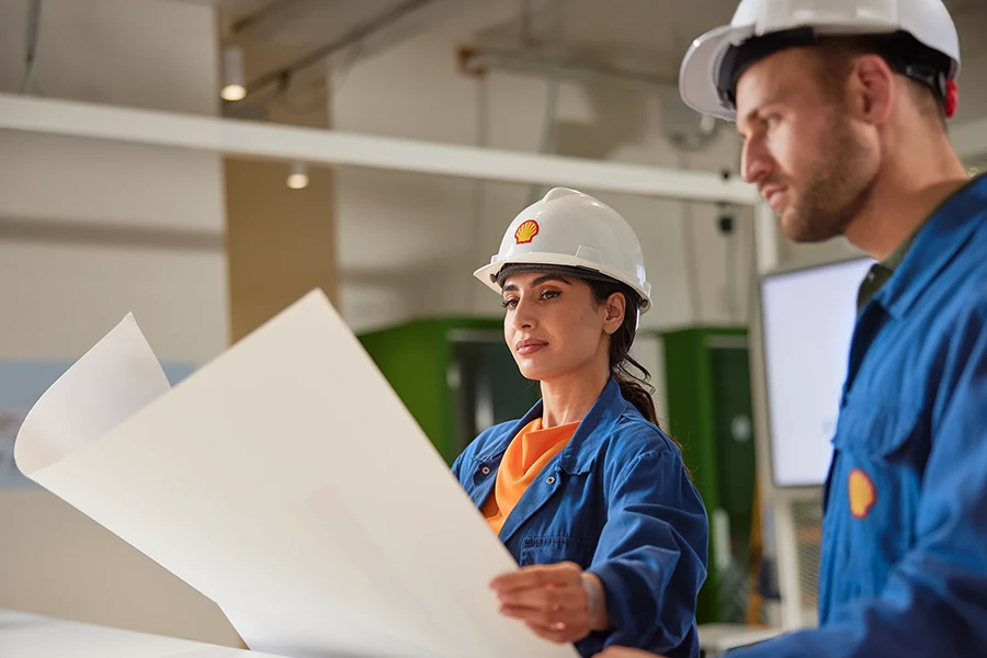 sbrs-weitere-themen-loesung-services Zwei Ingenieure überprüfen Pläne in einem Büro – symbolisieren die Planung von SBRS EV-Ladelösungen und Infrastruktur.