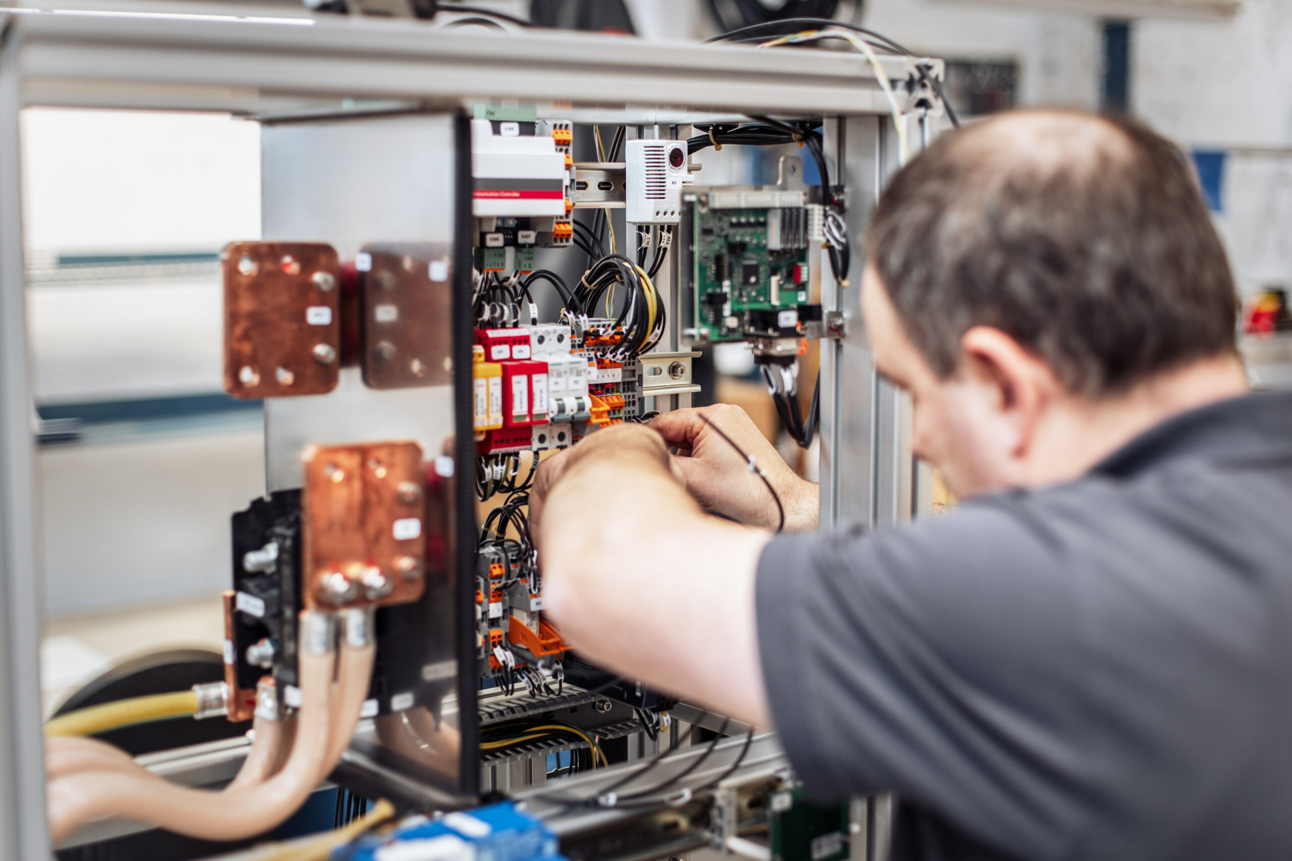 Technician working on the internal wiring of a modular charging hardware unit at a workbench.